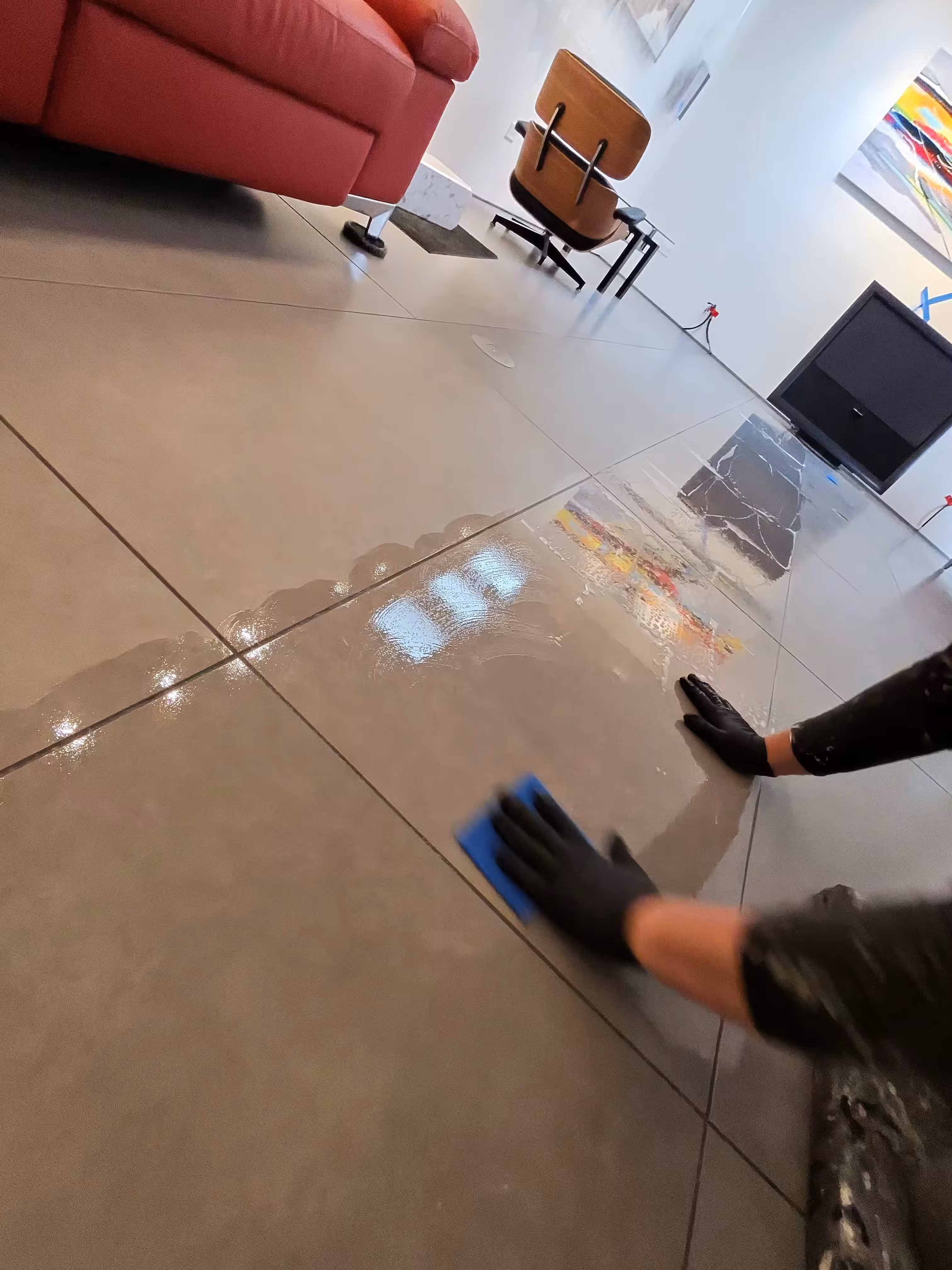 Blue non-scratch sponge being used to gently remove epoxy residue from tile
